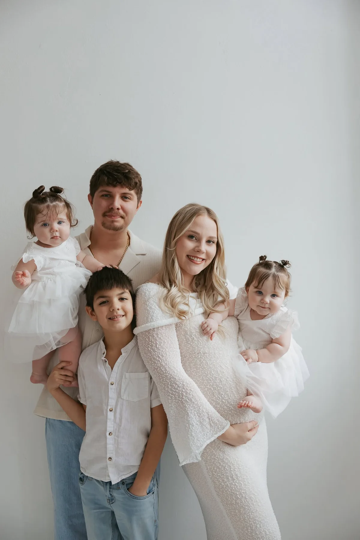 Cole Dockery and his family posing together in light-colored clothing against a neutral background.